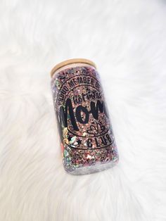 a can with glitter on it sitting on top of a white fur