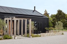 a black building with doors and windows in front of some trees on the other side