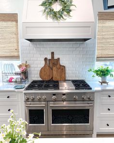 a kitchen with white cabinets and stainless steel stove top oven, surrounded by greenery