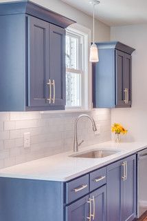 a kitchen with blue cabinets and white counter tops