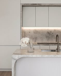 a kitchen with marble counter tops and white cabinets, along with a sink in the center