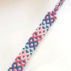 a red, white and blue beaded bracelet on a white surface with a black hook