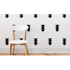 a white chair sitting in front of a wall with black arrows on it