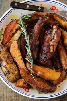 a white plate topped with meat and potatoes on top of a wooden table next to a knife