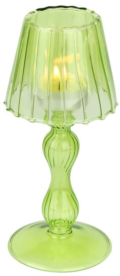 a green glass table lamp with a lit candle in it