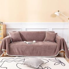 a living room with a couch covered in a blanket and two pillows on the floor