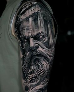 a man's arm with a black and grey tattoo on it, depicting the face of an ancient greek god