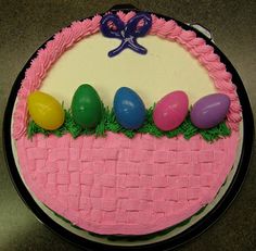 a cake decorated with pink icing and colored eggs