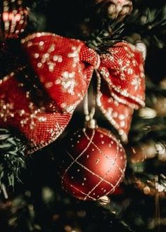 a red christmas ornament hanging from the top of a tree with ornaments on it