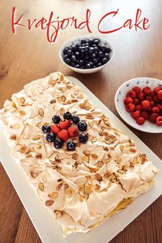 a cake sitting on top of a white plate next to berries and other desserts