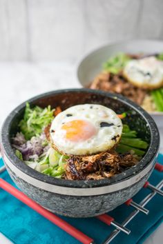 a bowl filled with meat and an egg on top of some vegtables