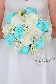 a bridal holding a bouquet of white and blue flowers on her wedding day,