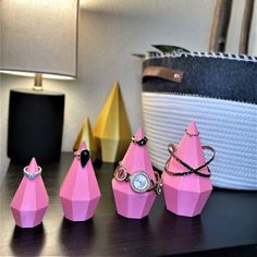 three pink rings are sitting next to each other on a table in front of a basket and lamp