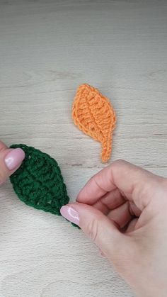 someone is crocheting an orange and green leaf