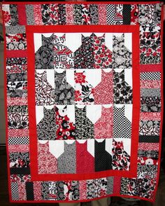 a red and black quilt hanging on a wall