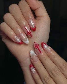 This almond-shaped nail design captures the essence of holiday joy with a blend of red glitter tips and intricate snowflake patterns. A standout feature is the accent nail adorned with a delicate red bow, reminiscent of a beautifully wrapped Christmas gift. The combination of white, red, and clear polish creates a look that is both festive and refined, perfect for any holiday gathering. Design Nails Christmas, Almond Shaped Nails Designs Christmas, Christmas Design Nail Art, Good Christmas Nails, Nails Cristhmas 2023, Christmas Nails Elegant Red, Gift Wrap Nails, Almond Holiday Nails Christmas, Christmas Nail Designs Red And White