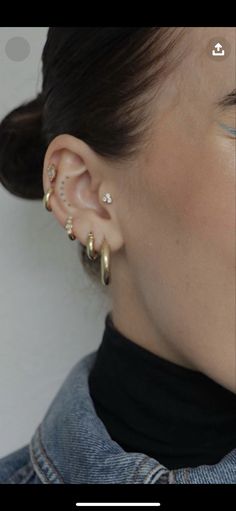 a close up of a person with ear piercings on their ears and wearing a denim jacket