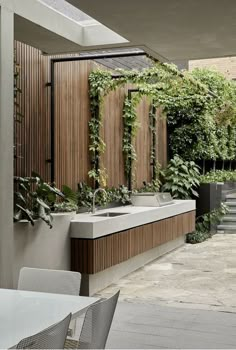 an outdoor kitchen with plants growing on the wall and sink in the center, surrounded by greenery