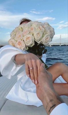 a bride and groom holding hands while sitting on the back of a boat in the water