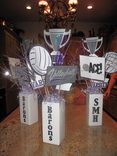 three vases with volleyball and basketball trophies on them