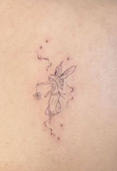 a small fairy tattoo on the back of a woman's left shoulder and chest