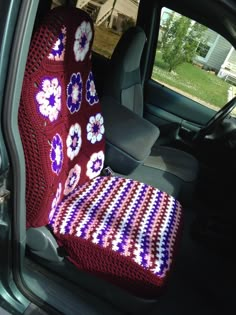 a car seat covered in a crocheted blanket with flowers on the front and back