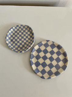 two blue and white checkered plates sitting on top of a table next to each other