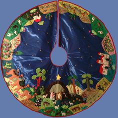 a blue christmas tree skirt with nativity scenes on it and a star hanging from the center