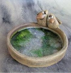 two little birds sitting on top of a wooden bowl filled with green algae and water