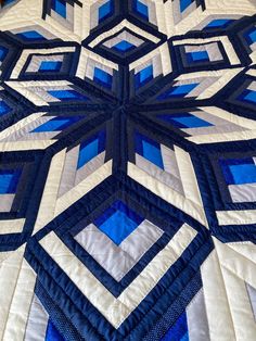 a large blue and white quilt on top of a bed