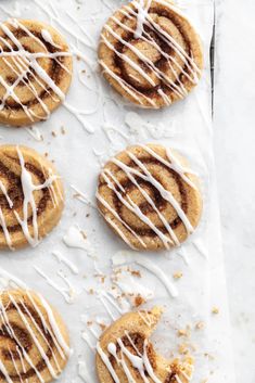 several cookies with white icing on a sheet of parchment paper