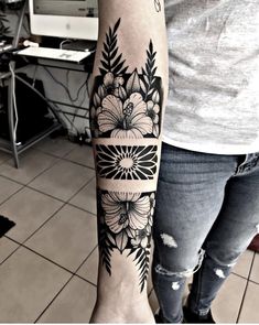 a woman's arm with black and white flowers on the left side of her forearm