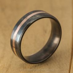 a wedding ring with two stripes on the inside of it, sitting on top of a piece of cardboard