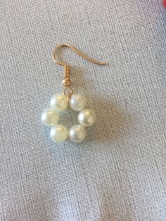 a pair of earrings with white pearls hanging from it's earwires on a gray surface