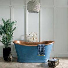 a blue bath tub sitting on top of a wooden floor next to a potted plant