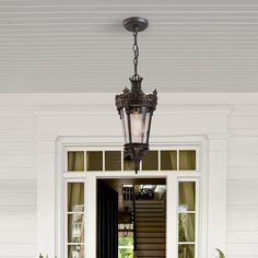 a light hanging from the side of a white door with potted plants in front of it