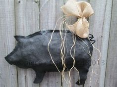 a black pig hanging on the side of a fence with a bow around its neck