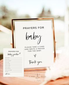 a wooden table topped with a sign next to a white feather and a thank you note