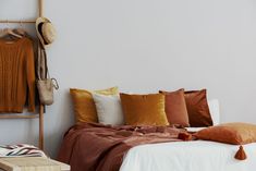 a bed with orange and white pillows on it next to a wall mounted coat rack