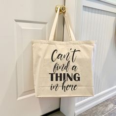 a tote bag hanging on the door handle that says, can't find a thing in there