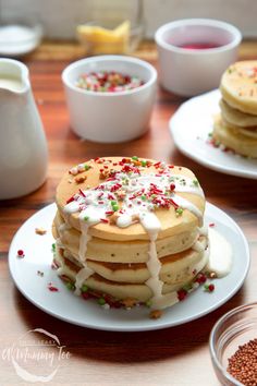 a stack of pancakes with white icing and sprinkles on a plate