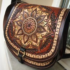 a brown leather purse with an intricate design on the front and sides, sitting on top of a counter