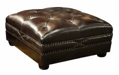 a brown leather ottoman sitting on top of a wooden table