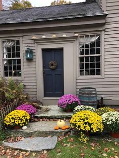 a house with flowers and pumpkins in the front yard