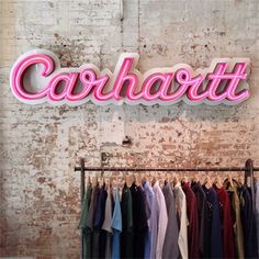 there is a sign that says carhart on the wall next to shirts and ties