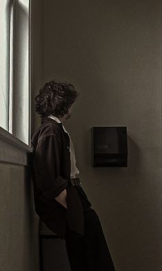 a woman leaning against a window sill looking out at the street and microwave on the wall