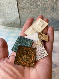 a person holding four different types of tile in their hand