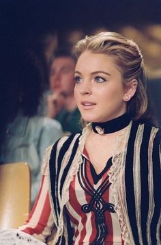 a woman sitting at a table wearing a striped shirt