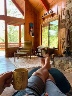 a man sitting on the floor with his feet up holding a coffee cup in front of him