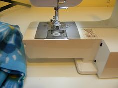 the sewing machine is sitting on the table next to the blue and white blanket that has been sewn